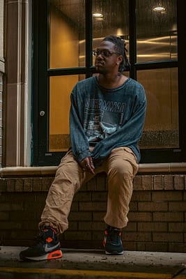 man sitting on wall near windows